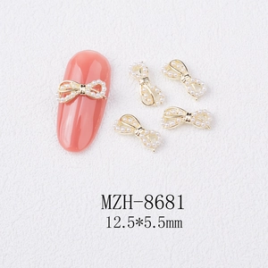 Detailed view of 3D alloy bow nail art charm with pearls on a coral manicured nail