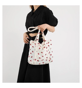 Detail of white corduroy tote bag featuring red and green strawberry prints on the fabric