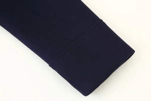Detaillierte Nahaufnahme der dunkelblauen Strickbündchen an einer kurzen Wolljacke