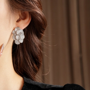 Gros plan de boucles d'oreilles fleurs plaquées or 18 carats portées par un mannequin