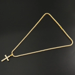 Detail of golden cross pendant with pearls and crystals on a tennis chain necklace