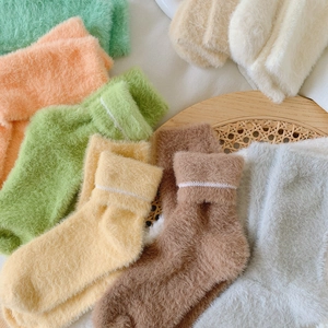 Detailed view of thick fuzzy socks in macaron colors on a woven rattan tray