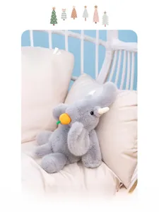 Détail d'un doudou éléphant gris avec carotte sur un coussin rose douillet