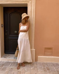 White sleeveless tiered maxi dress styled with straw hat and bag on a European street