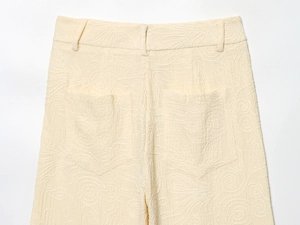 Détail du pantalon blanc cassé avec broderie en spirale et poches arrière
