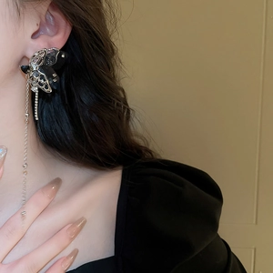 Detail of silver tassel earring with black diamond butterfly on model with soft lighting