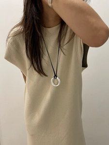 Detailed view of a thick silver circular pendant on a black cord necklace for women
