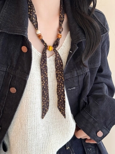 Detail of ethnic fabric beaded necklace with leopard print and wooden beads on a model