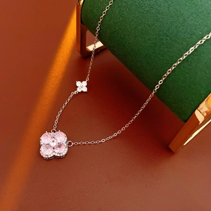 Macro detail of silver necklace featuring pink zircon clover pendant and bow element