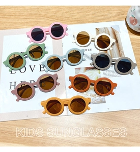 Flat lay display of 8 colorful matte round frame sunglasses for kids on a magazine