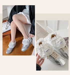 Close-up of silver sneakers with decorative white lace trim and metallic finish