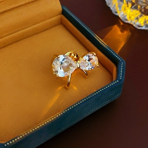Close-up of gold-plated bow brooch with sparkling zircons on orange velvet jewelry box