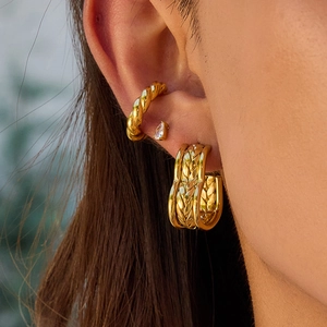 Golden heart earrings set with woven hoop and ear cuff shown on model's ear