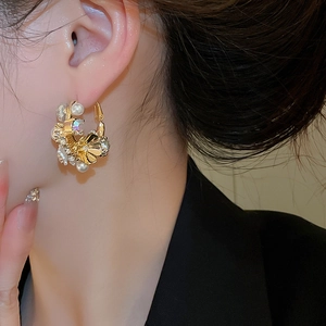 Macro side view of a model wearing vintage gold flower earrings with pearls and crystals