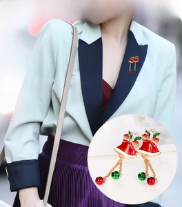 Close-up detail of a Christmas bell brooch with red rhinestones and alloy enamel finish