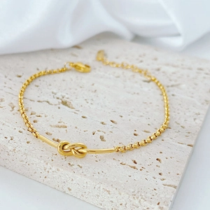 Minimalist 18k gold knot bracelet for women with adjustable chain on stone display