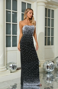 Detail of elegant black tube evening gown with white pearl embellishments in warm lighting