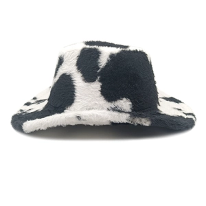 Dettaglio cappello bucket in finta pelliccia con stampa mucca bianca e nera in peluche