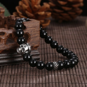 Macro detail of agate beads and silver skull charm on a men's stretch bracelet