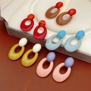 Detailed view of colorful oval resin earrings arranged on a velvet jewelry display