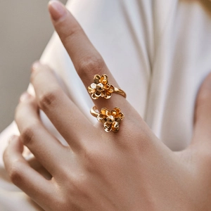 Detail of elegant gold double flower ring with 18K plating worn on a hand