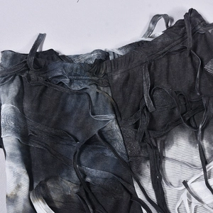 Dettaglio di pantaloni in maglia tie-dye con bordi invecchiati e coulisse con nappe decorativi