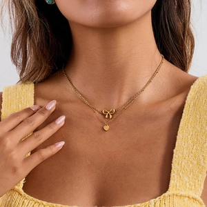 Double-layer stainless steel bow and heart pendant necklace worn by a fashion model