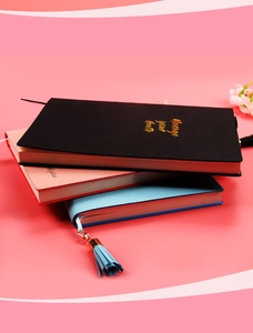Tre agende per dimagrire in rosa, blu e nero con nappe su uno sfondo morbido e decorativo