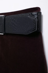 Détail d'une jupe en daim rouge foncé avec ceinture noire texture crocodile