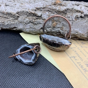 Détail macro de boucles d'oreilles en agate naturelle avec bords en bronze antique
