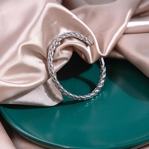 Close-up of silver braided metal cuff bracelet on silk background with elegant textures