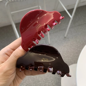 Close-up of red and dark brown acetate hair claws with gold Barrette La France text