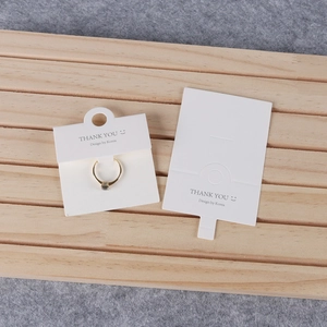 Minimalist white jewelry display card for rings on a natural wood background