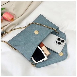 Blue envelope chain bag interior showing storage for phone, lipstick, and sunglasses
