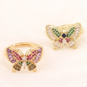 Macro shot of gold butterfly ring with colorful cubic zirconia on beige fabric