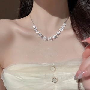 Close-up of elegant silver necklace featuring white flowers with pearls and crystals