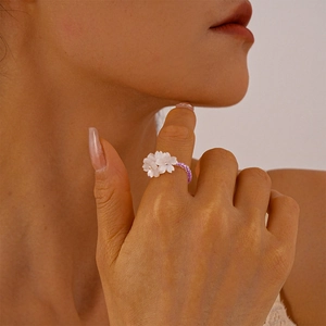 Detailed view of handmade beaded flower ring with purple beads and white floral charms