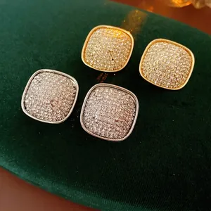 Square micro-pave rhinestone stud earrings in gold and silver on green velvet base