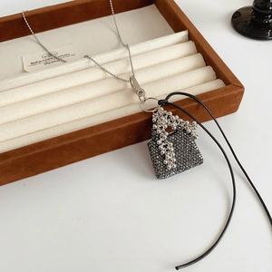 Gros plan du pendentif sac à main argenté avec glands de raisin dans un écrin à bijoux