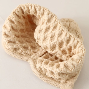 Close-up of cream white chunky knit baby hat showing thick honeycomb texture and soft yarn