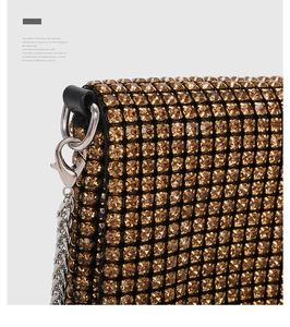 Detailed close-up of golden rhinestone evening bag with detachable silver chain strap