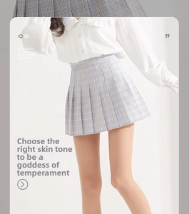 Detail view of blue and white plaid pleated JK skirt paired with a ruffled white shirt