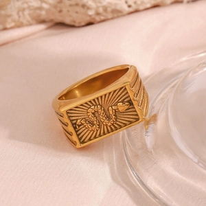 Macro detail of 18K gold plated ring with snake emblem and radial texture on pink silk