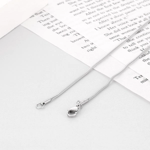 Close-up of a silver stainless steel lobster clasp on a chain over a vintage book page