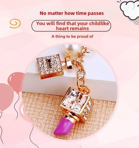 Detail of luxury rhinestone lipstick and perfume bottle keychain with faux pearls