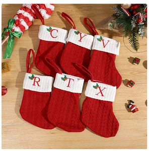 Detail of red knit Christmas stockings with white cuffs featuring embroidered letters