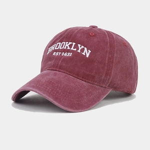 Close-up of white Brooklyn embroidery on washed burgundy cotton baseball cap fabric