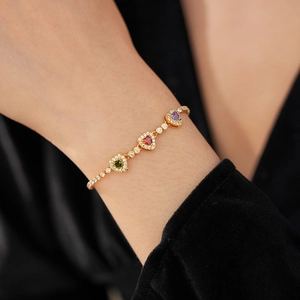 Detail of 18k gold plated heart bracelet with colorful zircons on a female wrist