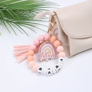 Detail of silicone bead keychain with MAMA letter beads and pink tassel on a leather bag