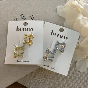 Mini metallic bow hair clips in gold and silver finish set on display cards